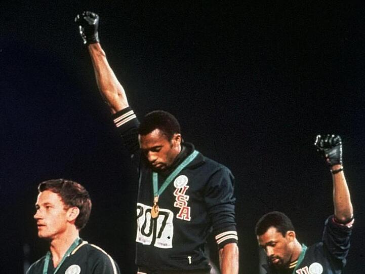 Die US-Athleten Tommie Smith (M) und John Carlos (r) streckten während Olympia 1968 die Fäuste, um gegen Rassismus zu protestieren.