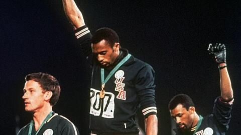 Die US-Athleten Tommie Smith (M) und John Carlos (r) streckten während Olympia 1968 die Fäuste, um gegen Rassismus zu protestieren.