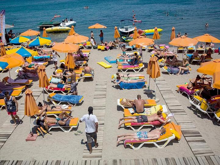 Touristen genießen die Sonne an einem Strand auf der griechischen Insel Kos.