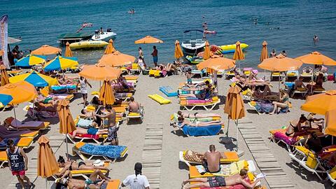 Touristen genießen die Sonne an einem Strand auf der griechischen Insel Kos.