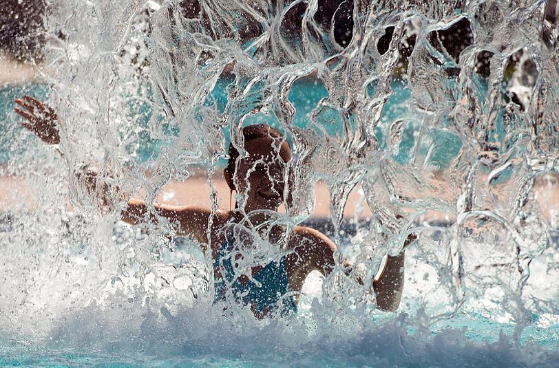 Ein Mädchen plantscht unter einem Wasserpilz in einem Freibad in Brandenburg. Foto: Patrick Pleul