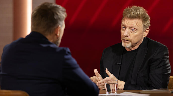 Boris Becker trägt im Interview mit Steven Gätjen Schwarz. Seine Haare sind länger und nun Kupfer-Blond. Das Gesicht wird kantiger, er hat an Gewicht verloren
