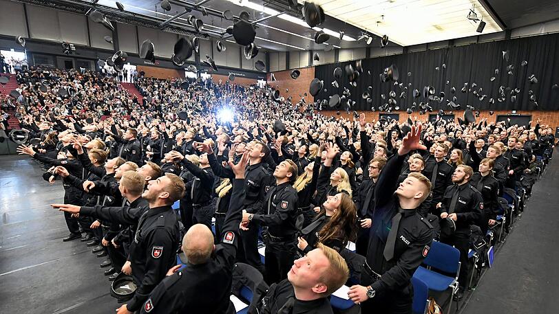 559 Absolventinnen und Absolventen der Polizeiakademie Niedersachsen werden während einer Feierstunde verabschiedet und werfen zum Ende des Festaktes ihre Polizeimützen in die Höhe.