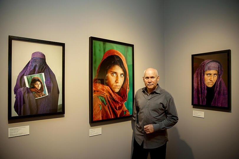 Fotograf Steve McCurry zwischen seinen Bildern.