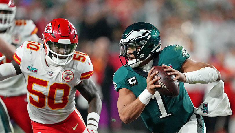 Eagles-Quarterback Jalen Hurts (r.) enteilt City-Chiefs-Linebacker Willie Gay.