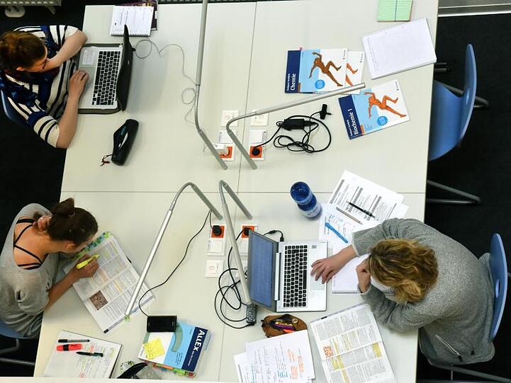 Studenten sitzen an einem Tisch. Foto: Waltraud Grubitzsch/Archiv