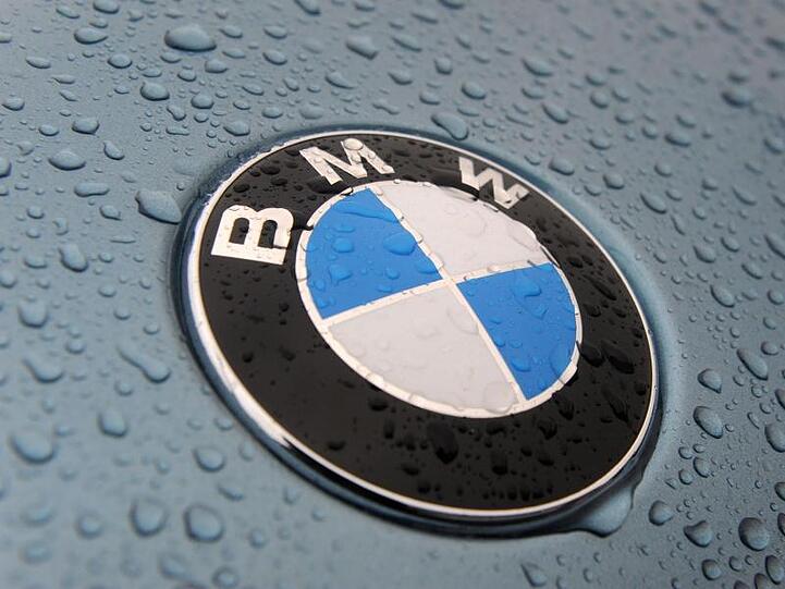 Das regennasse Firmenemblem eines BMW-Neuwagens ist zu sehen. Foto: Ingo Wagner/Archivbild