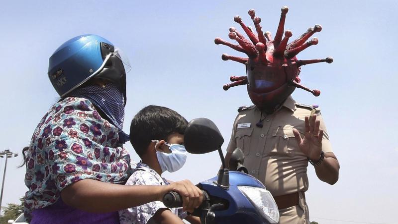 Ein Polizeibeamter im indischen Chennai trägt einen Helm, der einem Virus ähnelt, und weist Pendler auf die Einhaltung der Ausgangsbeschränkungen hin. Ein Polizeibeamter im indischen Chennai trägt einen Helm, der einem Virus ähnelt, und weist Pendler auf die Einhaltung der Ausgangsbeschränkungen hin.