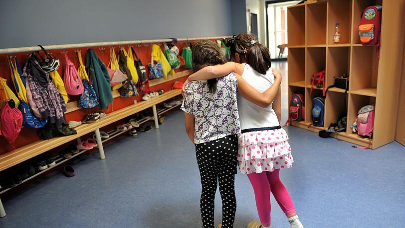 Zwei Mädchen gehen in einer Ganztagesschule in München Arm in Arm durch die Schule.