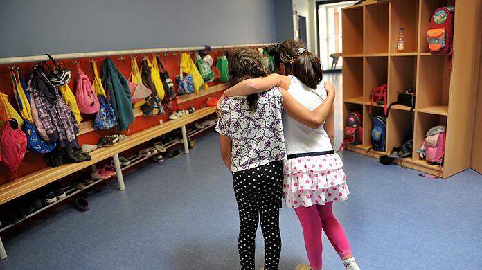 Zwei Mädchen gehen in einer Ganztagesschule in München Arm in Arm durch die Schule.