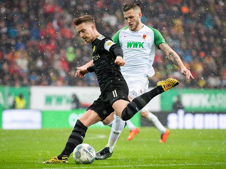 Dortmunds Marco Reus und Augsburgs Jeffrey Gouweleeuw (l-r.) am Werk. Foto: Tom Weller/dpa