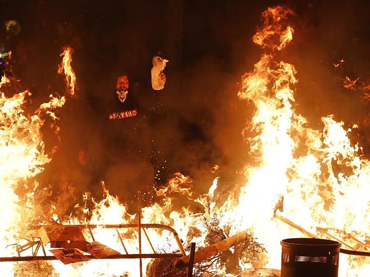 Ein Demonstrant steht in der Nacht vor einer brennenden Barrikade.