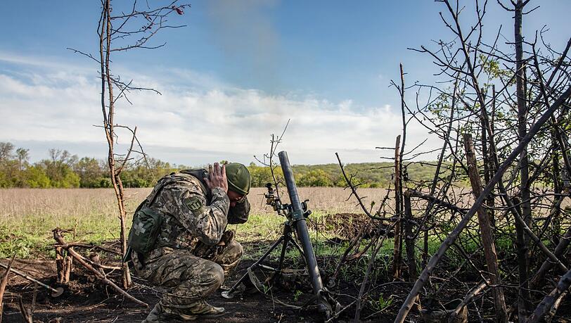Ein Soldat einer Mörser-Einheit der ukrainischen Streitkräfte hält sich die Ohren zu, während er auf feindliche Stellungen in den Vororten der Stadt Bachmut feuert.