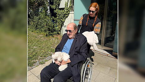 Ralph Siegel (80) wird von Ehefrau Laura (43) aus der Klinik abgeholt. Die ESC-Legende sitzt im Rollstuhl und h&auml;lt in den H&auml;nden Stofftier Hazy, welches an den verstorbenen Hund erinnert.