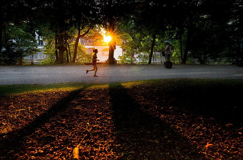 Spätsommer in München: Die Sonne blinzelt durch die angebräunten Blätter der Bäume am Isarufer. Für Jogger und Spaziergänger ein schönes Naturschauspiel.