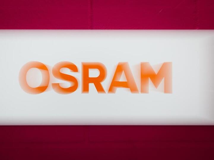 Das Osram-Logo steht auf weißem Hintergrund, der von zwei roten Streifen umrahmt wird. Foto: Matthias Balk/dpa/Archivbild
