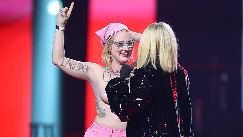 Avril Lavigne (re.) wollte die Oben-Ohne-Demonstrantin von der Bühne haben.