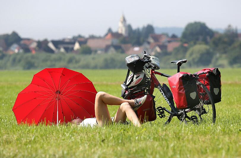 Eine Radtouristin macht am auf einer Wiese am Donau-Radwanderweg bei Daugendorf eine Pause. Foto: Thomas Warnack