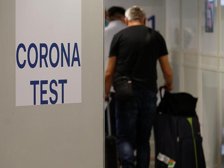 Reiserückkehrer gehen im Flughafen Düsseldorf zum Corona-Testzentrum.