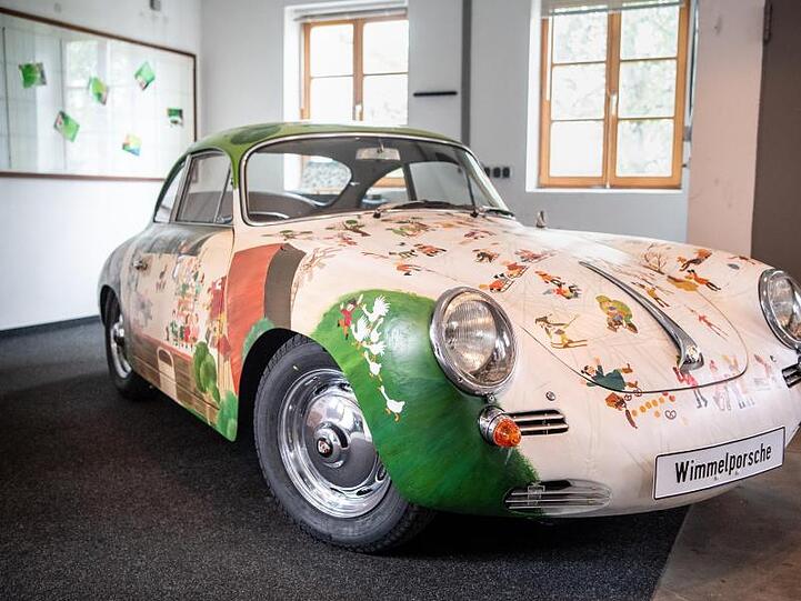 Ein mit Wimmelbildern verziertes Porsche 356 B Super 90 Coupé steht in einer Werkstatt. Foto: Matthias Balk/dpa