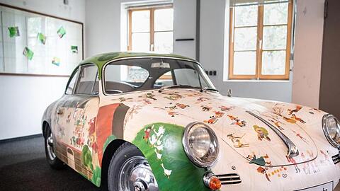 Ein mit Wimmelbildern verziertes Porsche 356 B Super 90 Coupé steht in einer Werkstatt. Foto: Matthias Balk/dpa