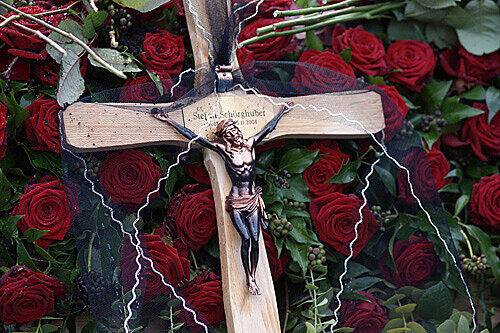 Ein schlichtes Kreuz auf roten Rosen ziert das Grab von Stefan Schörghuber