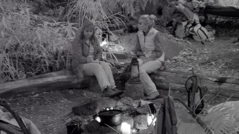 Tatjana Gsell (r.) kann Daniele im dunklem Camp nicht finden. Resigniert setzt sie sich zu Tina York ans Lagerfeuer.