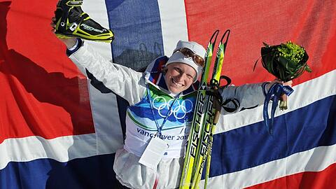 Olympiasiegerin Tora Berger posiert vor einer großen Norwegen-Fahne.