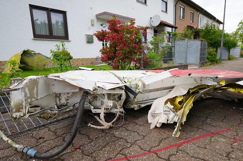 Tr&uuml;mmerteile eines Kleinflugzeuges liegen vor Wohnh&auml;usern, nachdem das Kleinflugzeug abgest&uuml;rzt war.