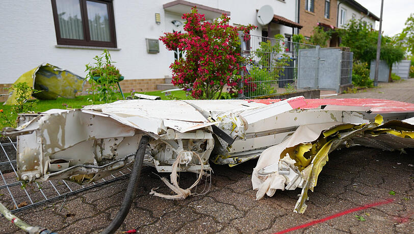 Trümmerteile eines Kleinflugzeuges liegen vor Wohnhäusern, nachdem das Kleinflugzeug abgestürzt war. Trümmerteile eines Kleinflugzeuges liegen vor Wohnhäusern, nachdem das Kleinflugzeug abgestürzt war.