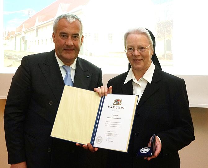 &bdquo;Der Preis bedeutet für mich Ehre und Wertschätzung&ldquo;, sagt die Oberin nach der Verleihung der Medaille. Sie nimmt die Ehrung für die Altöttinger Gemeinschaft Heilig Kreuz entgegen, die in den vergangenen Jahren seit 2011 das Landwirtschaftsgebäude der Gemeinschaft instandsetzen ließ.