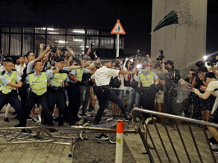 Polizisten setzen Pfefferspray gegen Demonstranten ein, die an dem Protest gegen das von der Regierung geplante Auslieferungsgesetz teilnehmen.