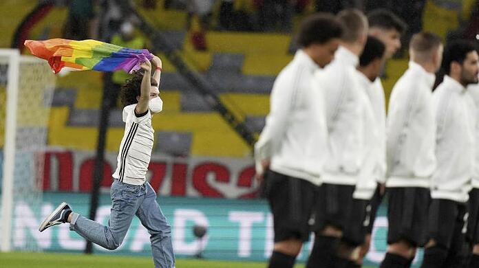 Während der ungarischen Hymne rennt der junge Mann mit Deutschland-Trikot und Regenbogen-Fahne aufs Feld.