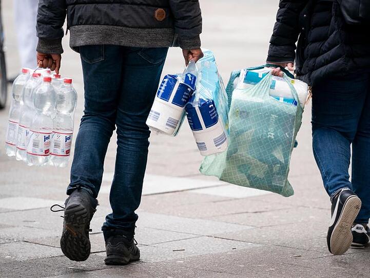 Passanten mit Toilettenpapier, Wasser und weiteren Einkäufen. Foto: Kay Nietfeld/dpa