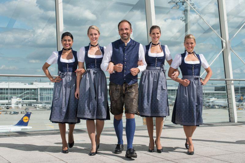 Das Wiesn-Dirndl der Flugbegleiterinnen ist dunkelblau mit silbergrauer Schürze. Die Herren tragen eine knielange Lederhose mit dunkelblauer Weste im Stoff des Dirndls.
