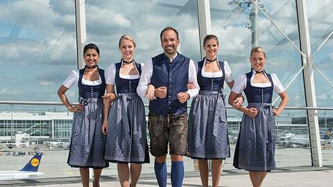 Das Wiesn-Dirndl der Flugbegleiterinnen ist dunkelblau mit silbergrauer Schürze. Die Herren tragen eine knielange Lederhose mit dunkelblauer Weste im Stoff des Dirndls.
