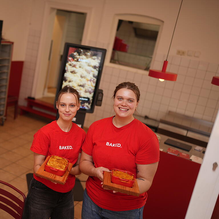 Hannah Eicher (r.) und Mitarbeiterin Lara pr&auml;sentieren die Aufl&auml;ufe bei Baked. In dem Lokal in der Maxvorstadt gibt es ausschlie&szlig;lich Gerichte aus dem Ofen.