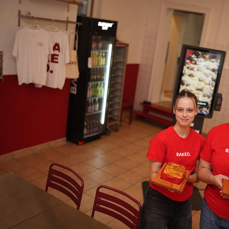 Hannah Eicher (r.) und Mitarbeiterin Lara pr&auml;sentieren die Aufl&auml;ufe bei Baked. In dem Lokal in der Maxvorstadt gibt es ausschlie&szlig;lich Gerichte aus dem Ofen.