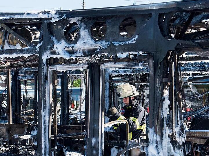 Ein Feuerwehrmann kontrolliert mit einer Wärmebildkamera ausgebrannte Busse auf einem Betriebshof im Stadtteil Wandsbek.