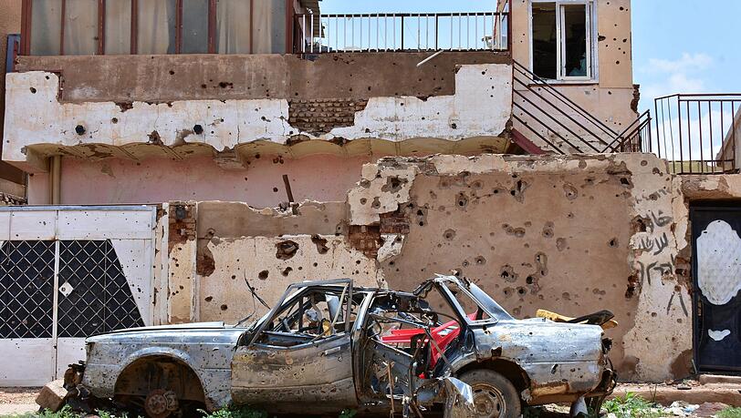 Ein zerstörtes Auto steht im sudanesischen Omdurman vor einem Haus voller Einschüsse. (Archivbild)