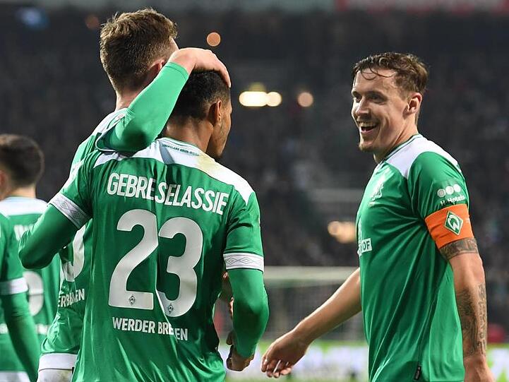 Werders Sebastian Langkamp (l) und Max Kruse (r) freuen sich mit dem Torschützen zum 1:1 Theodor Gebre Selassie.
