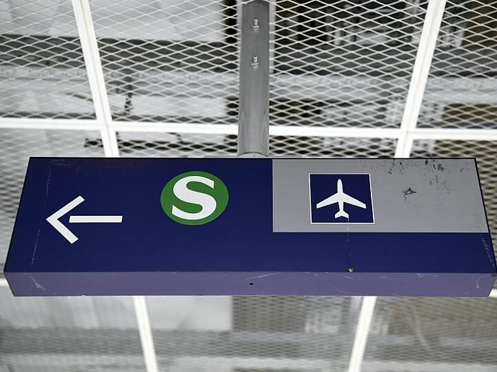 Das Logo der Münchner S-Bahn mit einem Richtungspfeil und einem Flughafen-Symbol.