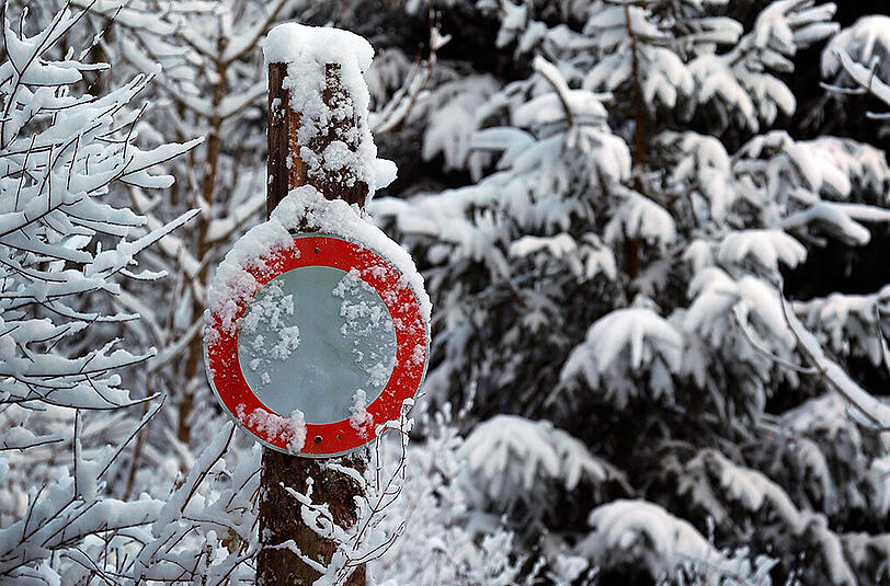 Den einzigen Farbkontrast bildet ein rotes Verkehrsschild am 22.11.2015 in einem winterlichen Wald bei Aitrang