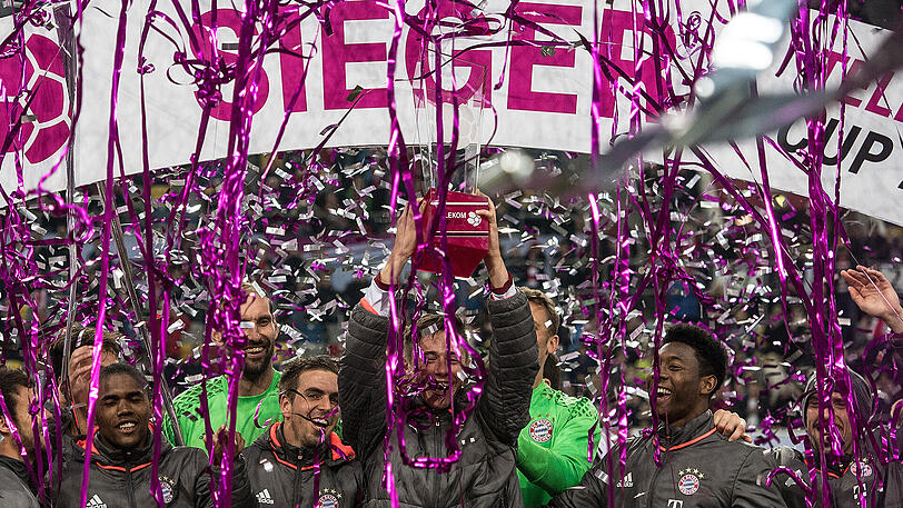 Manuel Neuer stemmt den Pokal in den Abendhimmel von Düsseldorf.