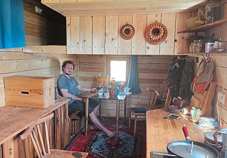 Samuel Meisinger an seinem Esstisch. Darüber befindet sich die Schlafkoje mit TV und Xbox.