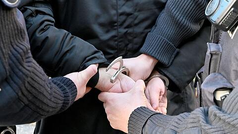 Polizisten legen einem Verdächtigen Handschellen an (Symbolbild).