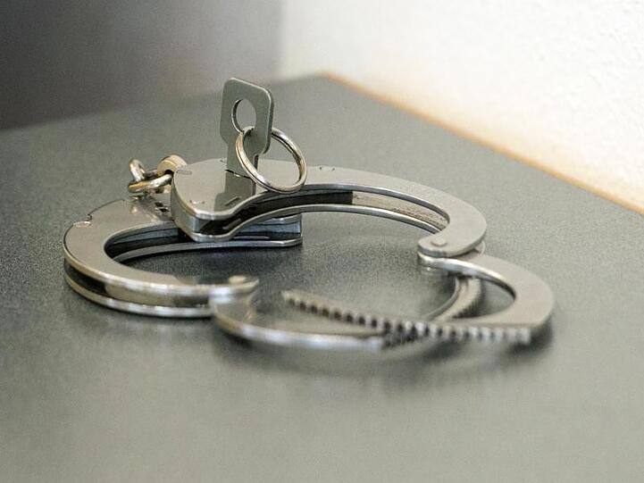 Handschellen liegen auf einem Tisch. Foto: Armin Weigel/dpa/Symbolbild