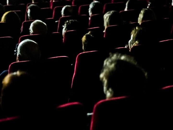 Besucher eines FernsehKrimi-Festivals sitzen in einem Kino. Foto: Nicolas Armer/dpa/Archivbild