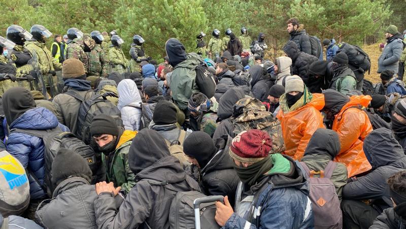 Migranten sitzen zusammen vor der Grenze in Belarus am gesperrten Übergang zu Polen.