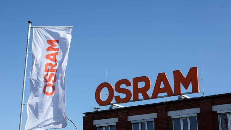 Eine Fahne mit dem Osram-Logo flatttert neben einem Gebäude im Wind.